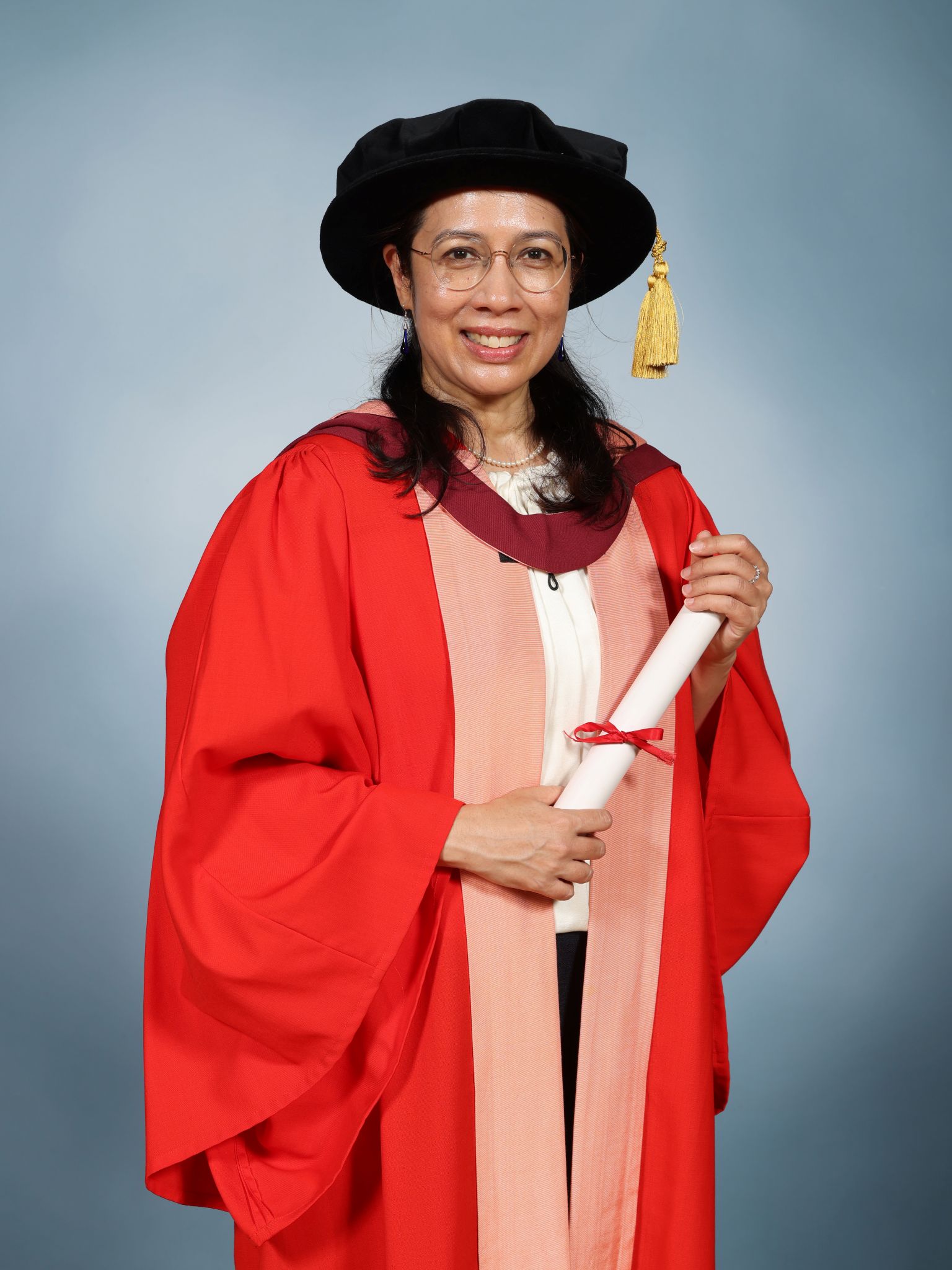 Sunita Rajakumar wearing a mortar board and holding a parchment